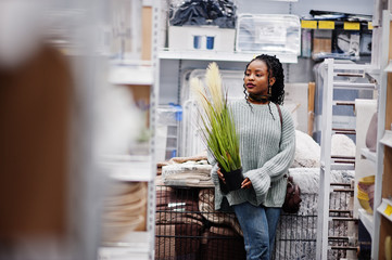 African woman choosing pot decoration for her apartment in a modern home furnishings store.