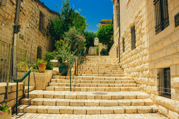 Jerusalem holy land city old street landmark Middle East urban view stairway between stone buildings in park outdoor district with green trees and plants in bright clear weather day time 