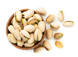 Pistachios spilled from a wooden plate on a white. The view of the top.
