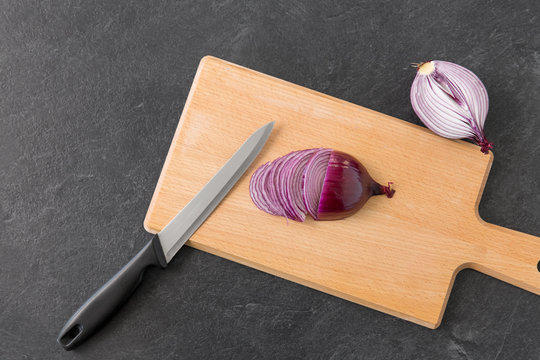 vegetable, food and culinary concept - chopped red onion and kitchen knife on wooden cutting board - Powered by Adobe