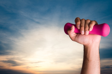 human hand holds dumbbell with morning light background