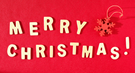 Fototapeta na wymiar Words Merry Christmas and red decorative snowflake on the red background. Flat lay, top view