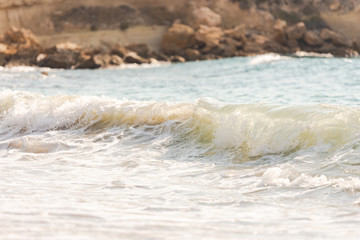 Mediterranean surf. Small waves roll on the shore. Sea foam on the beach.