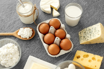 food and eating concept - close up of cottage cheese, bottle of milk, homemade yogurt with butter and chicken eggs on stone table