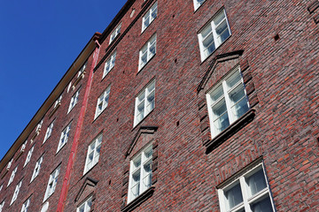 Fototapeta na wymiar Red stone white windows building house in streets of Helsinki european city. Good architecture elements composition