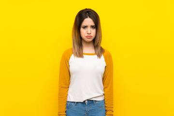 Pretty young woman over isolated yellow wall with sad and depressed expression