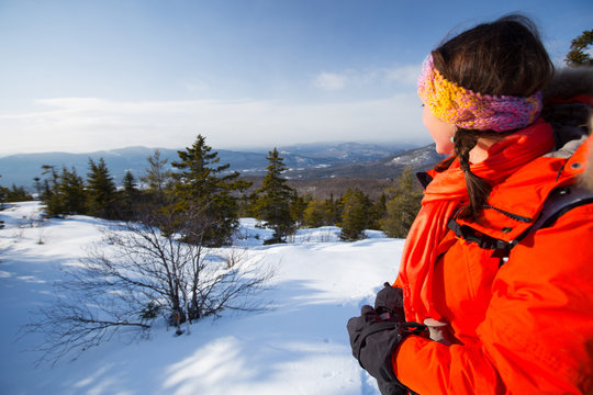 A woman takes in the dramatic vews of the Presidential Range and surrounding hills of the Mount Washington Valley while snowshoeing along Black Cap Mountain Trail near the summit of Black Cap Mountain in the Green Hills Preserve near North Conway, New Hampshire.