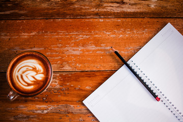 Blank notebook white screen with coffee on wooden table