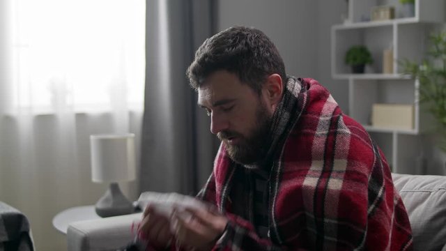 The sick man blows his nose in a napkin in the living room