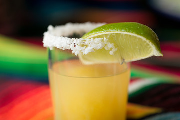 Margarita cocktail with tequila, orange liqueur, lime juice, with a salted rim, and garnished with a lime wedge.