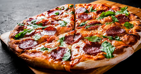 Pepperoni Pizza with Mozzarella cheese, salami, Tomato sauce, pepper, Spices and Fresh arugula. Italian pizza on Dark grey black slate background