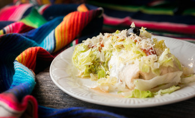 Burrito with refried beans, rice, chicken, topped with lettuce, sour cream, guacamole, Monterey jack cheese, and salsa.