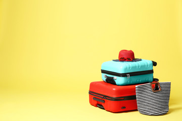 Stylish suitcases with hat and bag on yellow background. Space for text