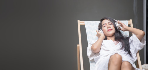 Beautiful girl relaxing poolside beauty concept.happy girl smile and listen to music with headphones.woman sleep on the chair and listen ear phone.