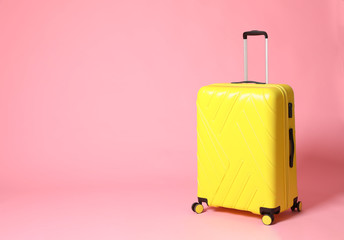 Stylish yellow suitcase on pink background. Space for text