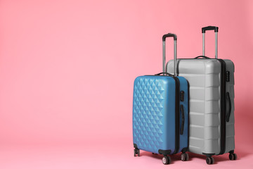 Stylish grey and blue suitcases on pink background. Space for text