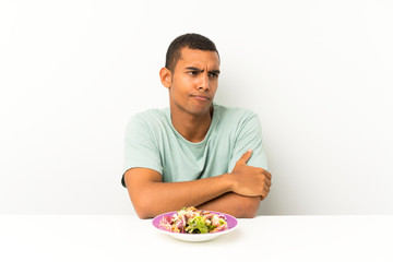 Young handsome man with salad in a table thinking an idea