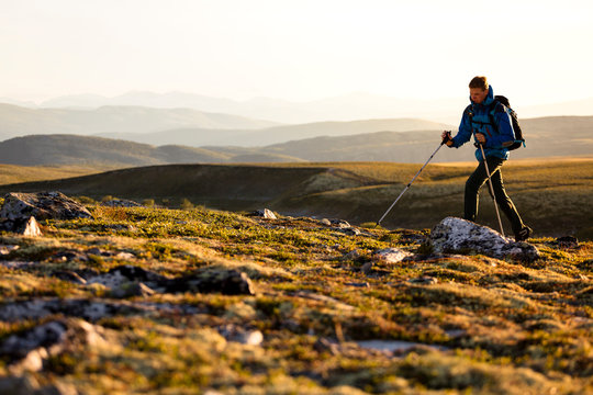 Rondane National Park, Norway: A male hiker hiking on a trail from the parking in Spranget towards Rondvassbu in the evening light.