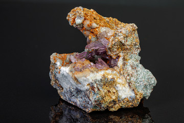 macro mineral amethyst stone in rock on a black background