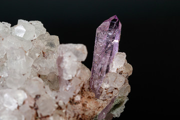 macro mineral amethyst stone in rock on a black background
