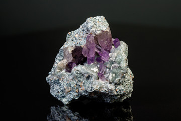 macro mineral amethyst stone in rock on a black background