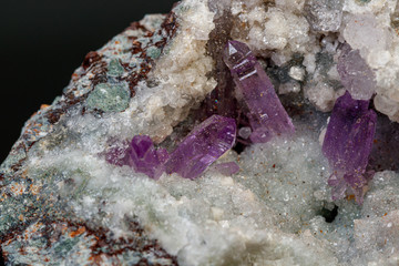 macro mineral amethyst stone in rock on a black background