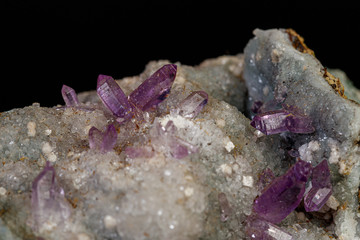 macro mineral amethyst stone in rock on a black background