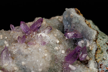 macro mineral amethyst stone in rock on a black background