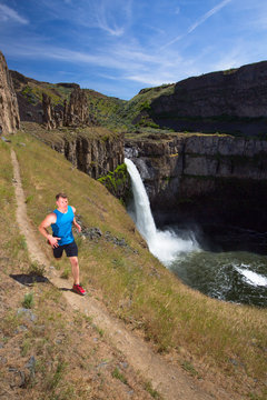 Fitness trainer goes for an exposed trail run around the rim of the Palouse Falls in southeastern Washington State. The short-but-scenic trail drops down from the main parking area and runs along the Palouse River, falls and surrounding ampitheater.