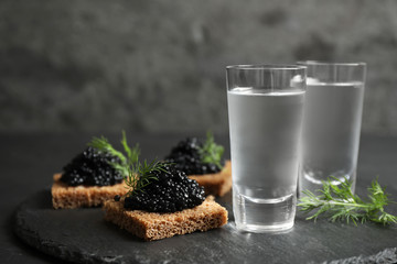 Fototapeta na wymiar Cold Russian vodka and sandwiches with black caviar on table, closeup