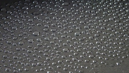 viele wassertropfen auf einer dunkelgrauen fläche