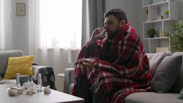 Ill man uses nasal spray on sofa in living room