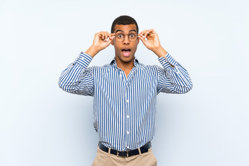Fototapeta premium Young handsome brunette man over isolated blue background with glasses and surprised
