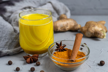 Golden milk with spices. Turmeric, cloves, black pepper and a drop of vegetable oil. Traditional indian drink. On a light background. Healthy eating Copy space. 