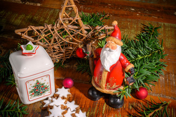 Christmas scene with cinnamon stars, a ceramic biscuit tin and other christmas decoration on an old wooden table.