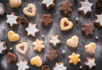 Assorted Christmas cookies with powdered sugar on the dark background, top view