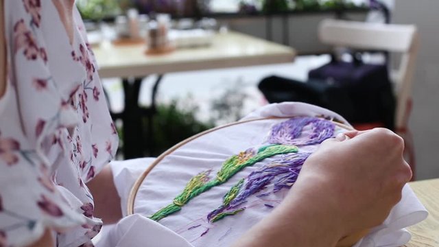 Female hands with vitiligo sewing with needle. embroidery hoop, embroidered fabric with colorful pattern, close up. Traditional hobby, lifestyle. Needlework, handicraft