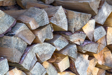 A lot of firewood outdoor, chopped wood stacked for the winter, brown background.