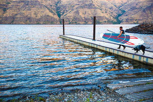 A man sets out on an early morning SUP session in southeast on the Snake River with his black lab Dora in tow.