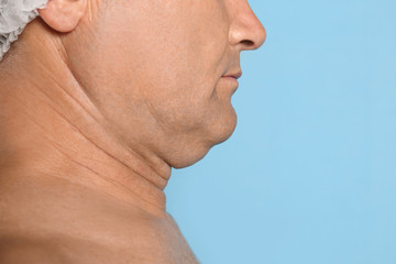 Mature man with double chin on blue background, closeup. Space for text