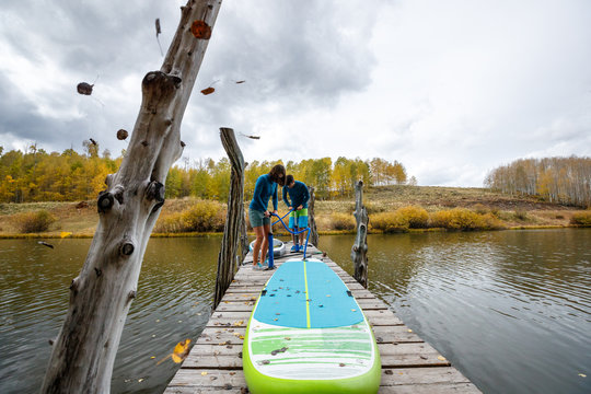 A man and a woman prepare their inflatable stand up paddle boards for SUPing in an alpine lake in the San Juan Mountains, Colorado in autumn.
