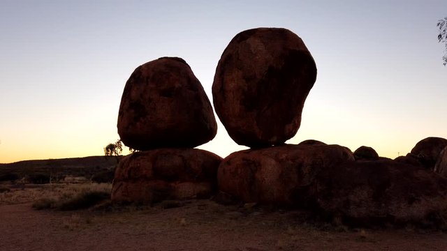 TIME LAPSE: Australia, Northern Territory. Aboriginal land in Red Centre. Sunbeams in sky at sunset behind iconic the Eggs of mythical Rainbow Serpent at Karlu Karlu Devils Marbles Reserve.