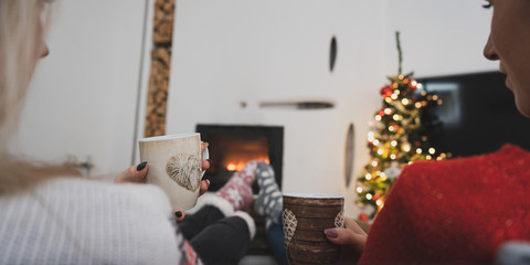 Two girlfriend enjoying by the fireplace at holiday season