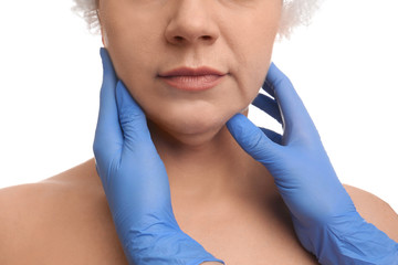 Doctor examining mature woman on white background, closeup. Double chin surgery