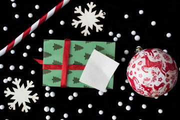 Christmas decoration with candy stick, handmade ornament ball, snowflake wooden tiles and gift box on black background.