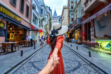 Touristinnen, die die Hand des Mannes halten und ihn zum Galata-Turm in Istanbul, Türkei, führen. © tawatchai1990