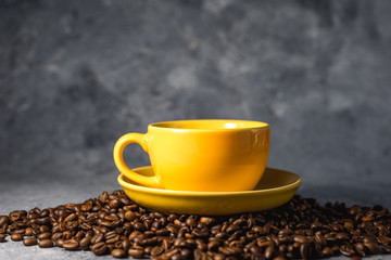 cup of coffee with beans on gray stone background
