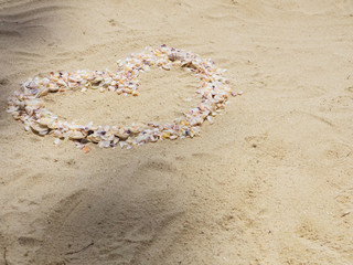 The heart on the sand is made of seashells as a symbol of love. Selective focus