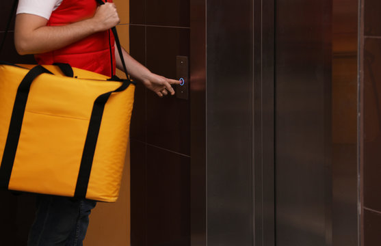 Male courier with thermo bag pushing elevator button, closeup. Food delivery service