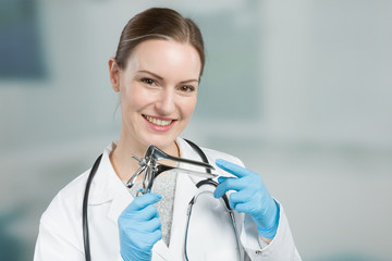 smiling female gynecologist with a speculum in her hand